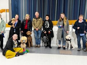 Group with dogs indoors, smiling at camera.