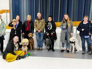Group with dogs indoors, smiling at camera.