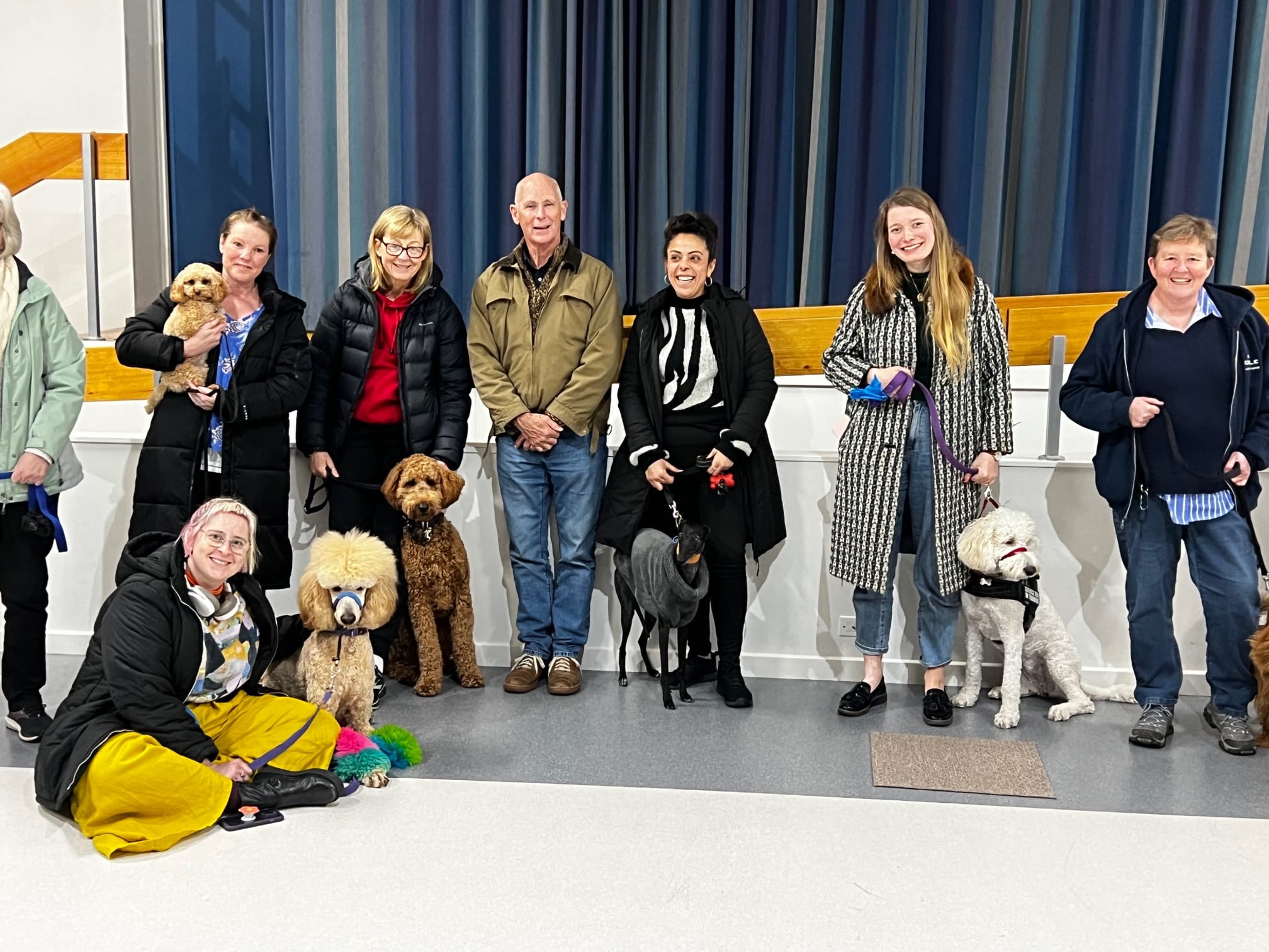 Group with dogs indoors, smiling at camera.