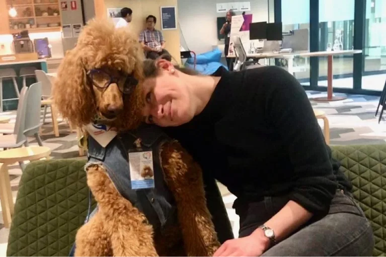 Certified Support Dog with official badge and vest getting a cuddle from its handler.
