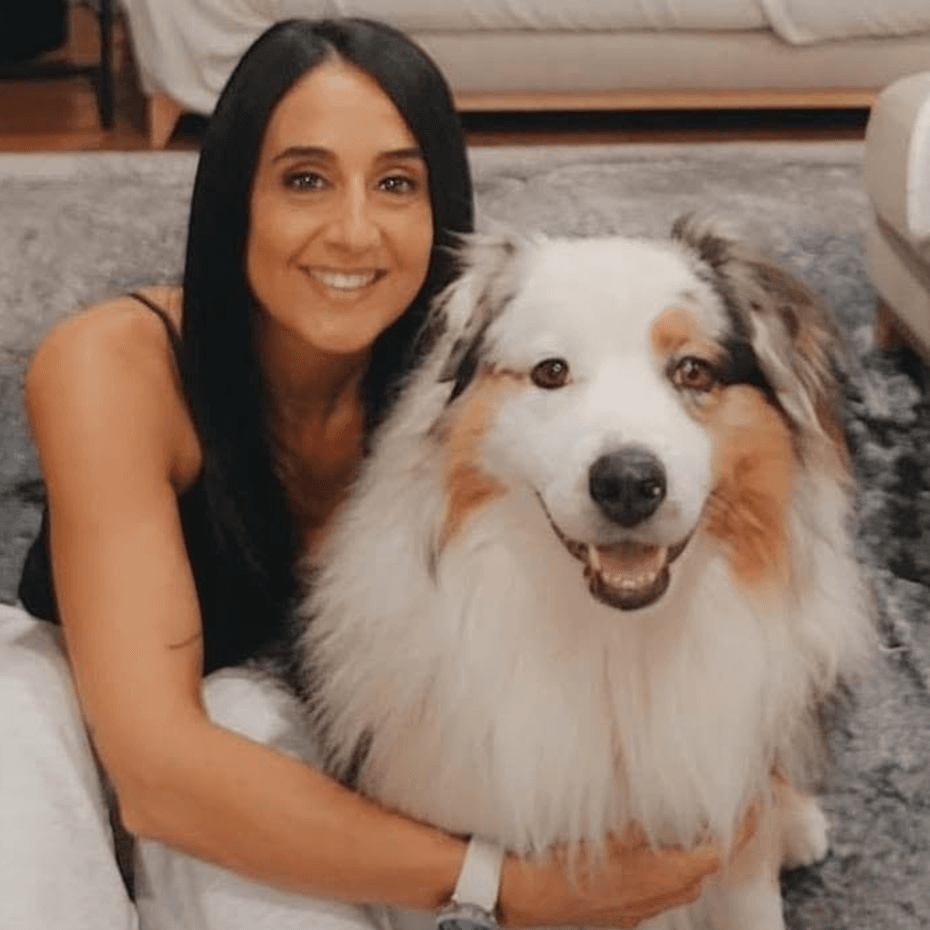 Smiling woman cuddling a fluffy dog indoors.
